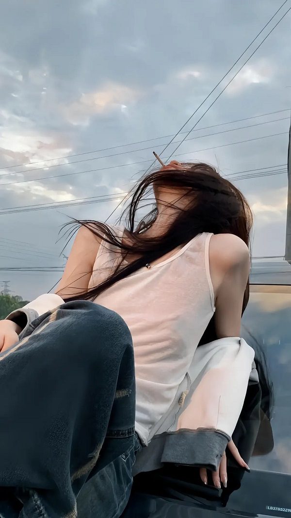 Thiếu nữ ngồi co gối ôm mặt bên bờ hồ